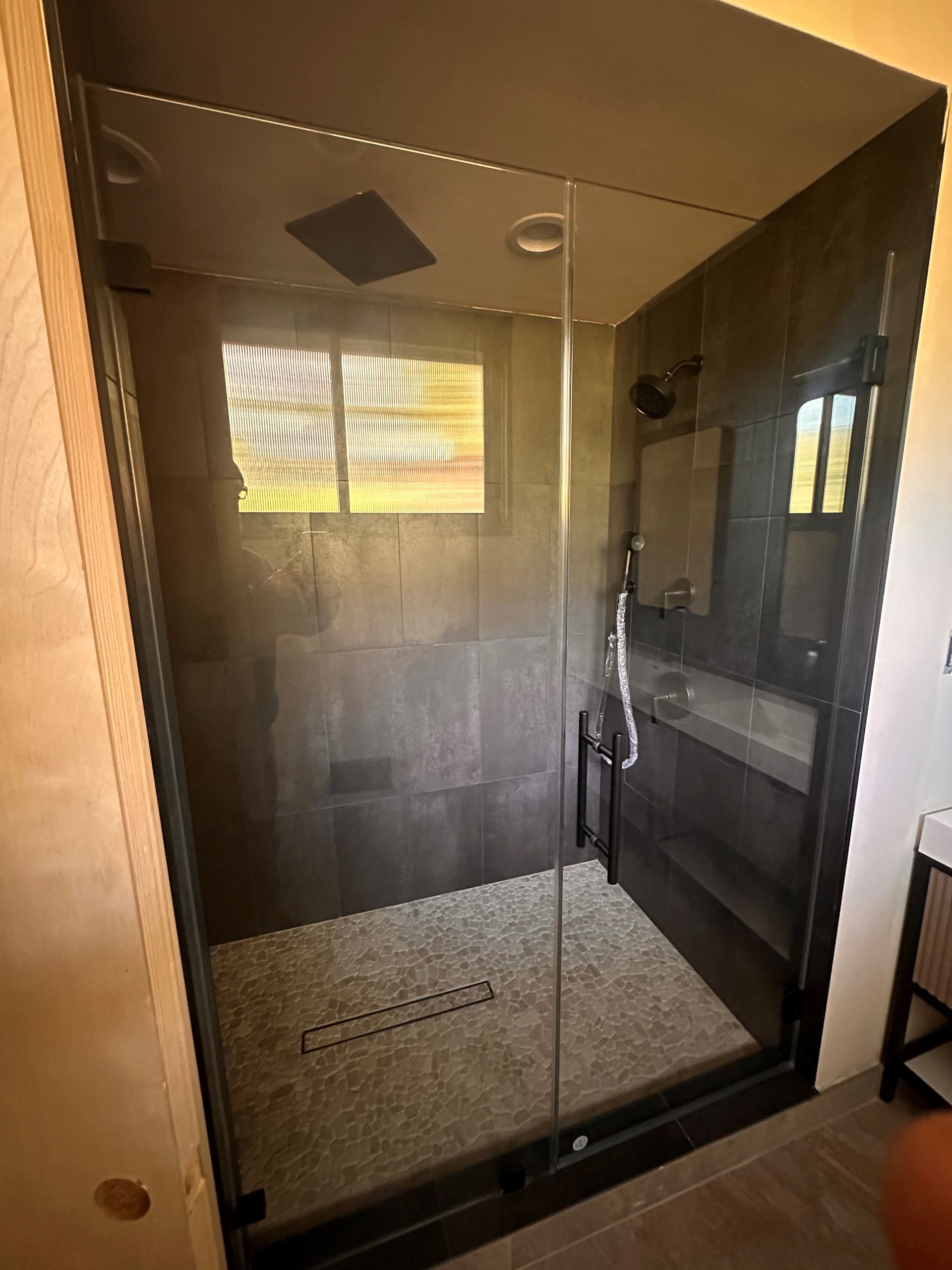 A man is shaking hands with a woman in a kitchen while holding a toolbox.