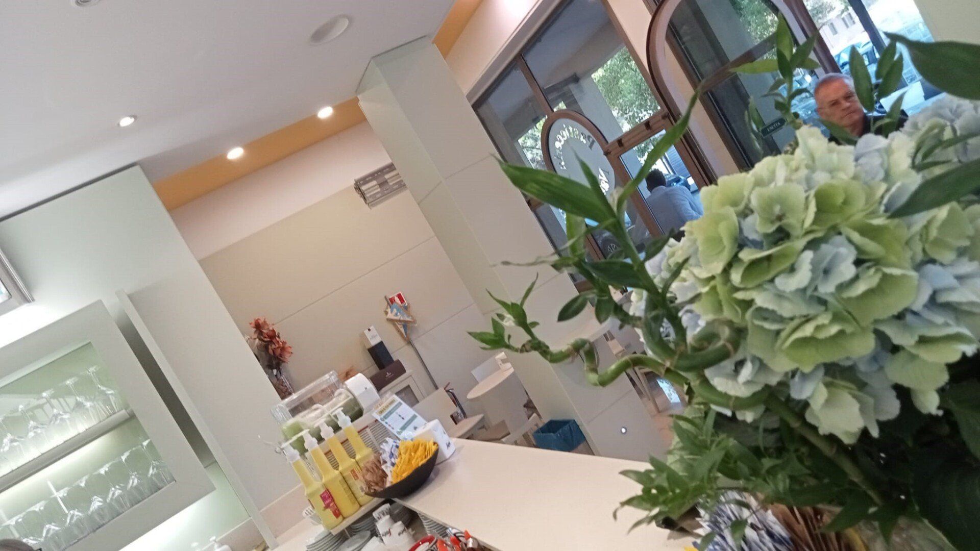 Fiori in un salone, con un uomo e l'interno visibili.