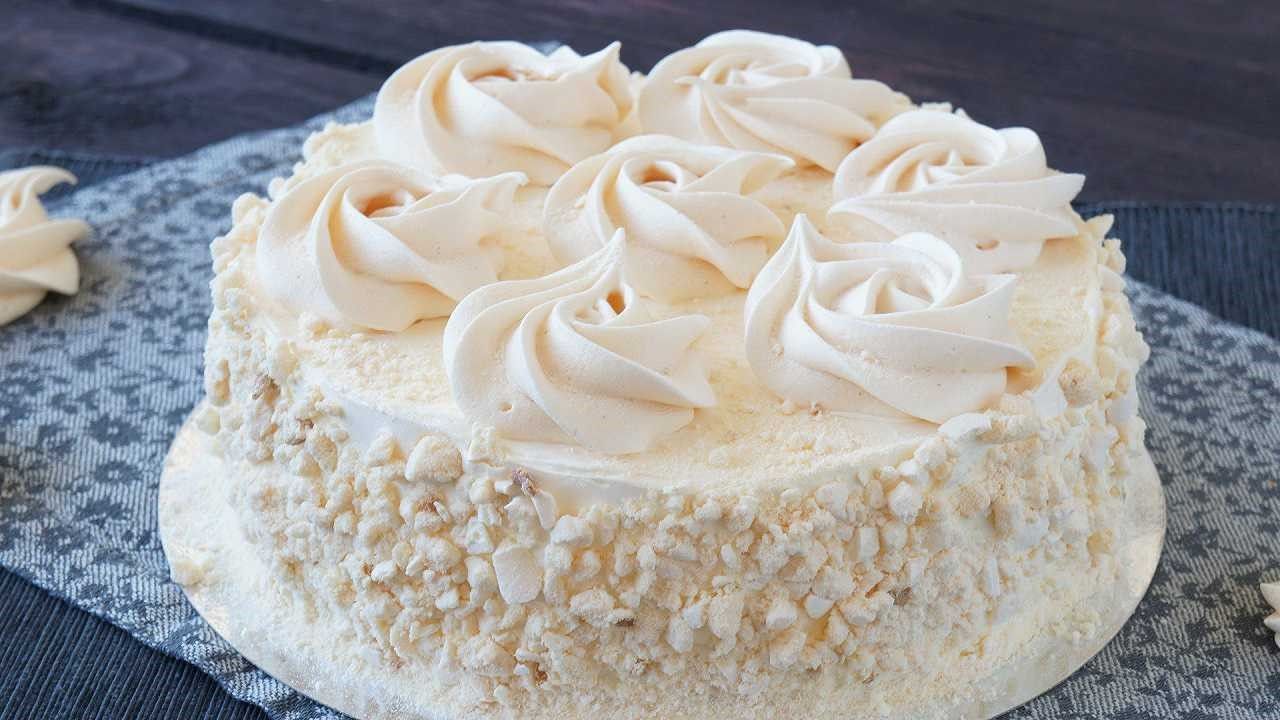 Torta con glassa bianca e noci tritate, sfondo in tessuto blu.