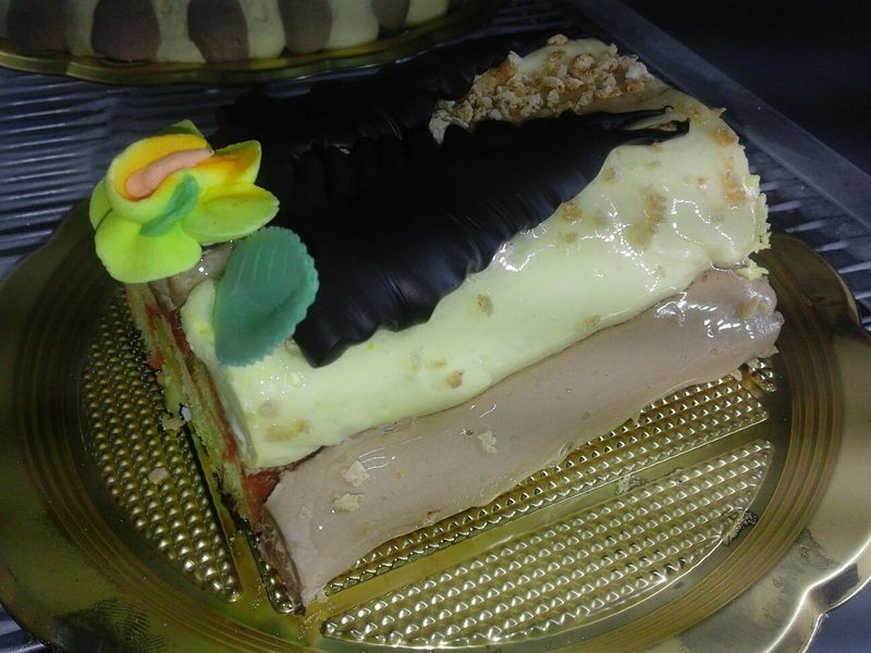 Fetta di torta a strati con glassa chiara e scura e un fiore decorativo.