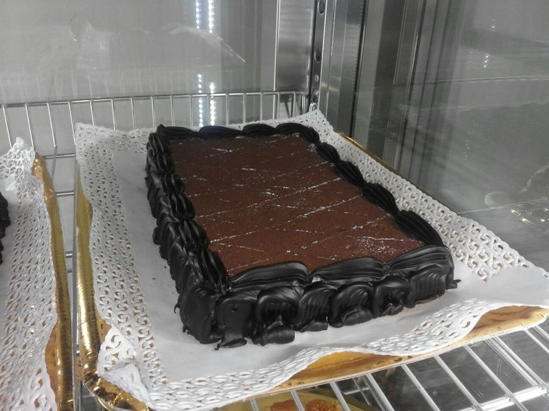 Torta al cioccolato esposta su uno scaffale in una teca di vetro.