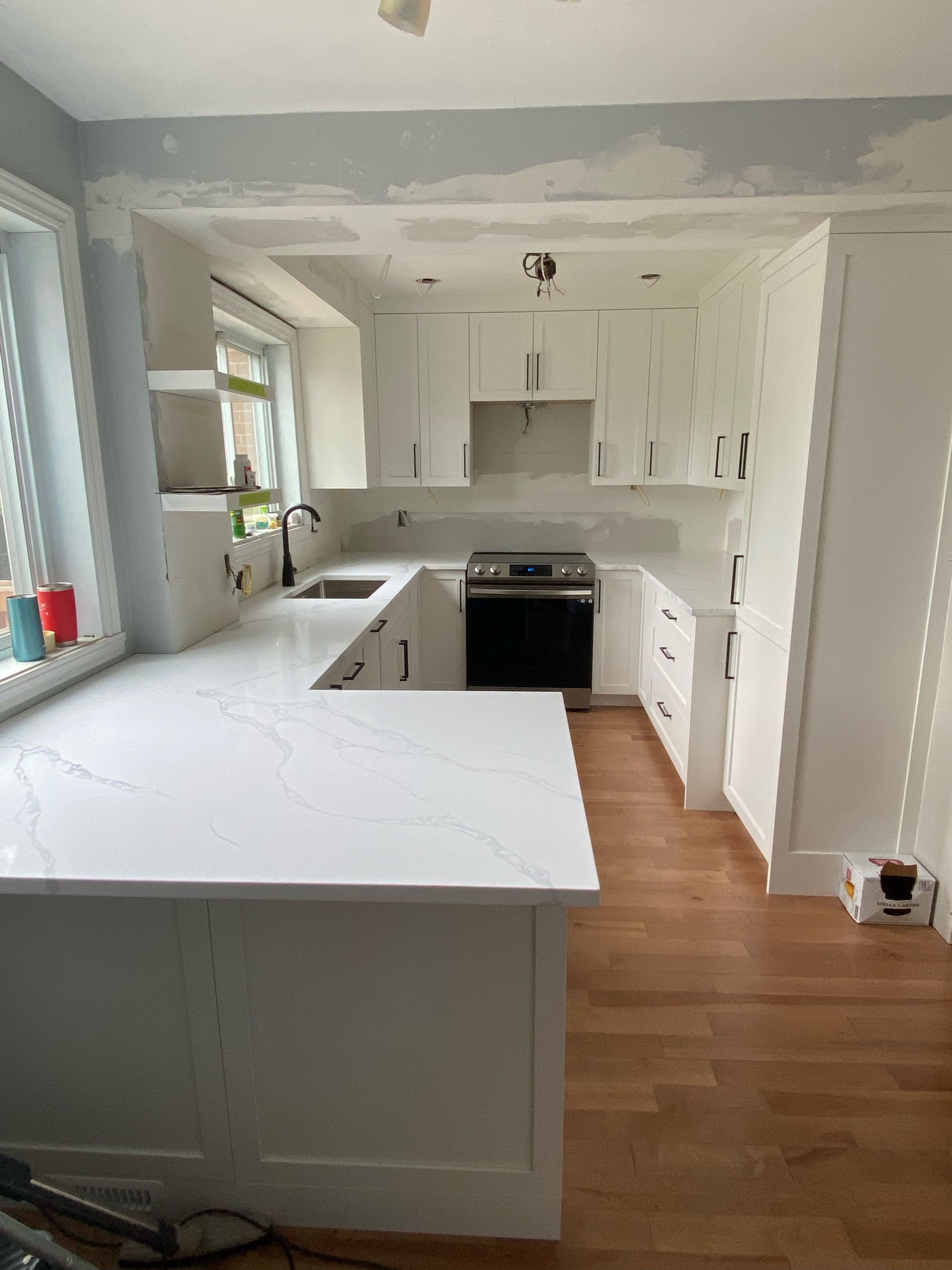 Une cuisine avec des armoires blanches, une cuisinière, un évier et un grand îlot.