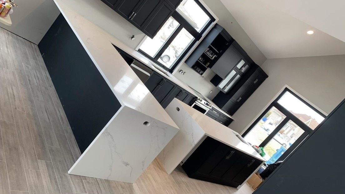 Une cuisine avec des armoires noires et des comptoirs blancs