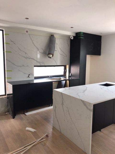 Une cuisine avec un grand îlot et des armoires noires