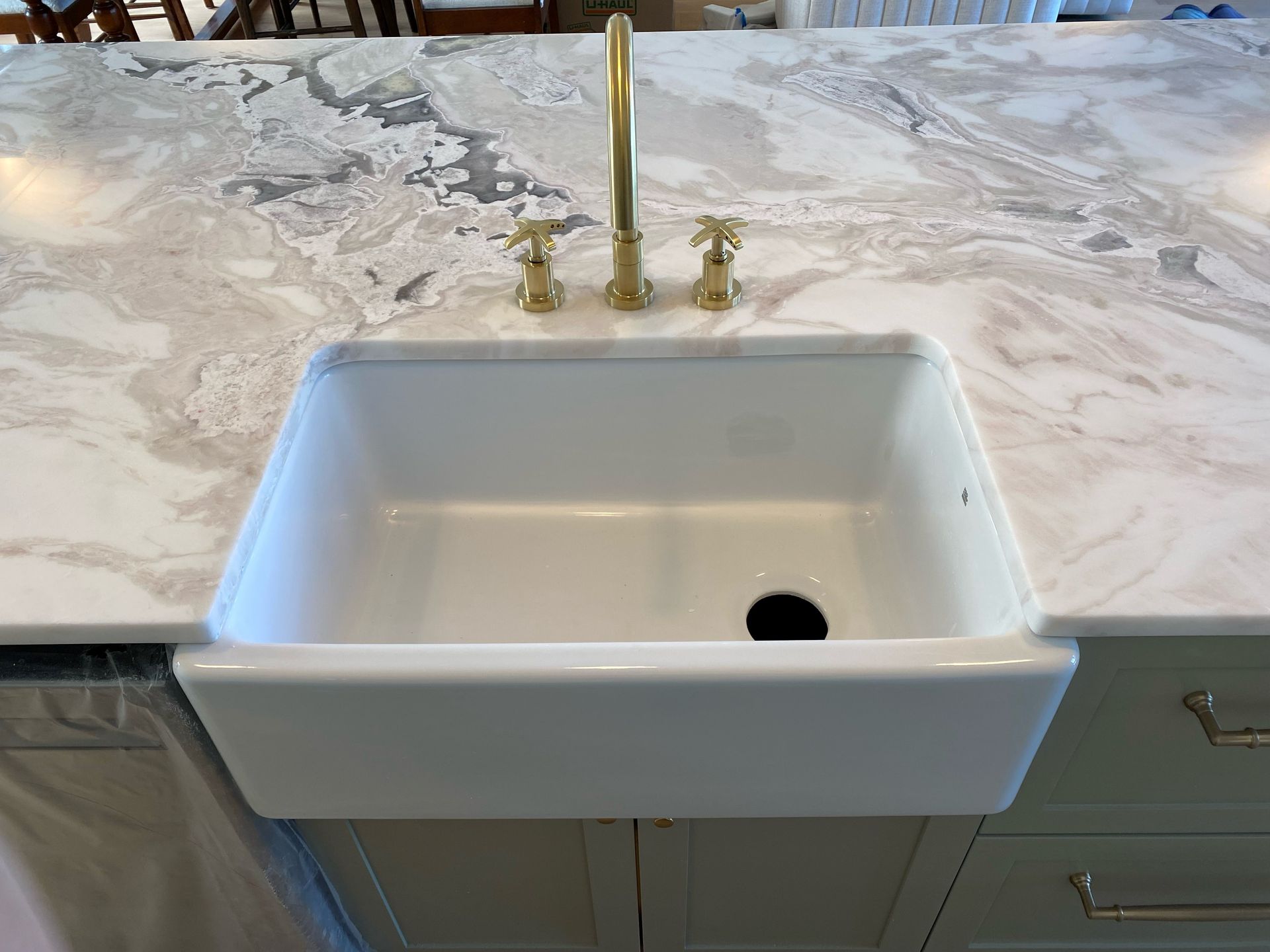 Un évier de ferme blanc est posé sur un comptoir en marbre.