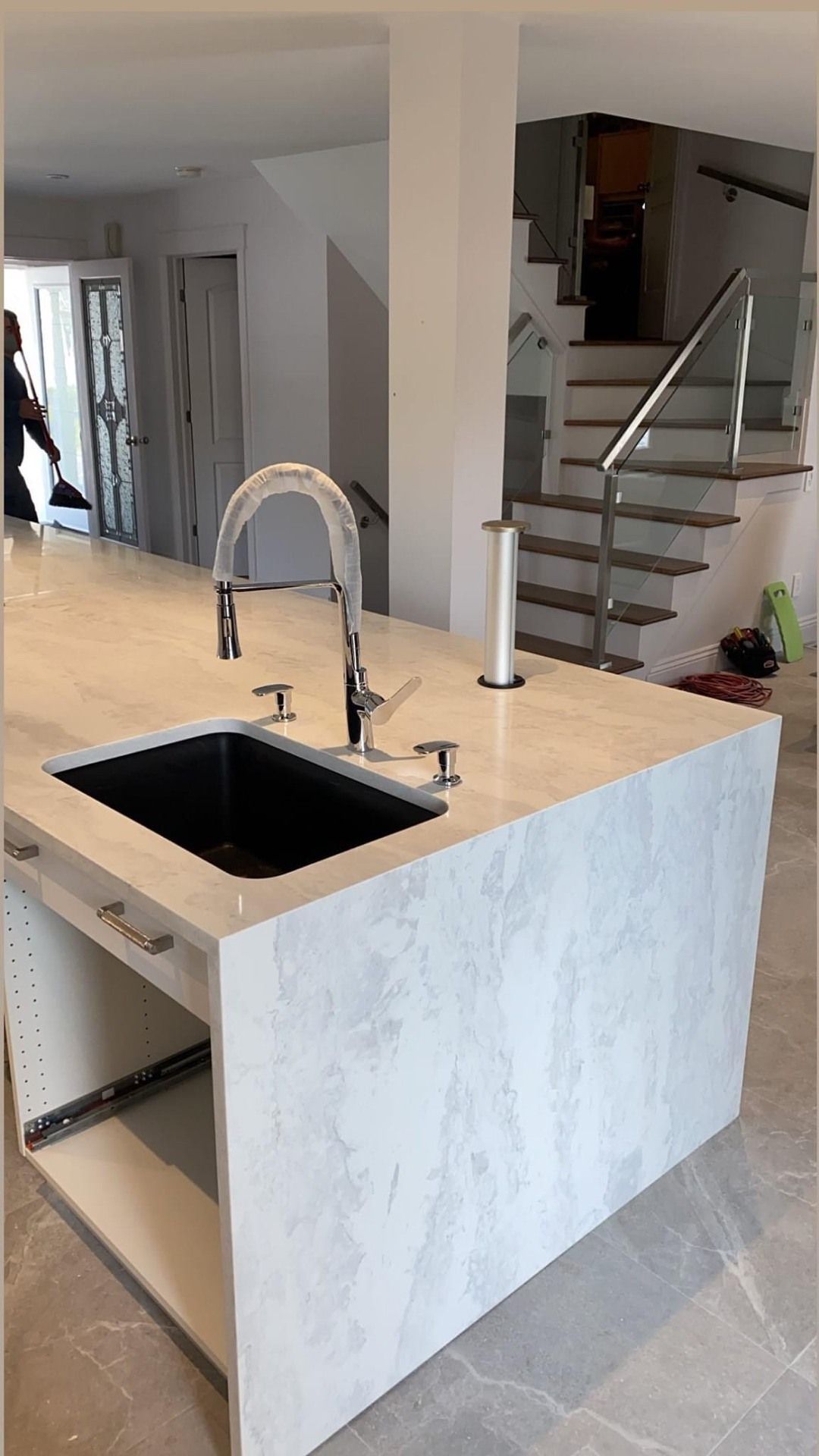 Une cuisine avec un évier et un escalier en arrière-plan.