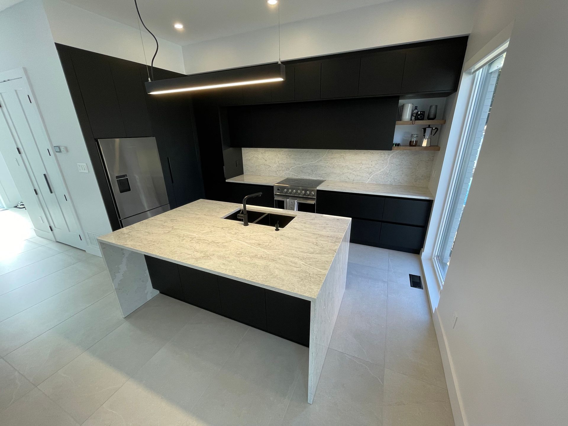 Une cuisine avec des armoires noires et un comptoir blanc.