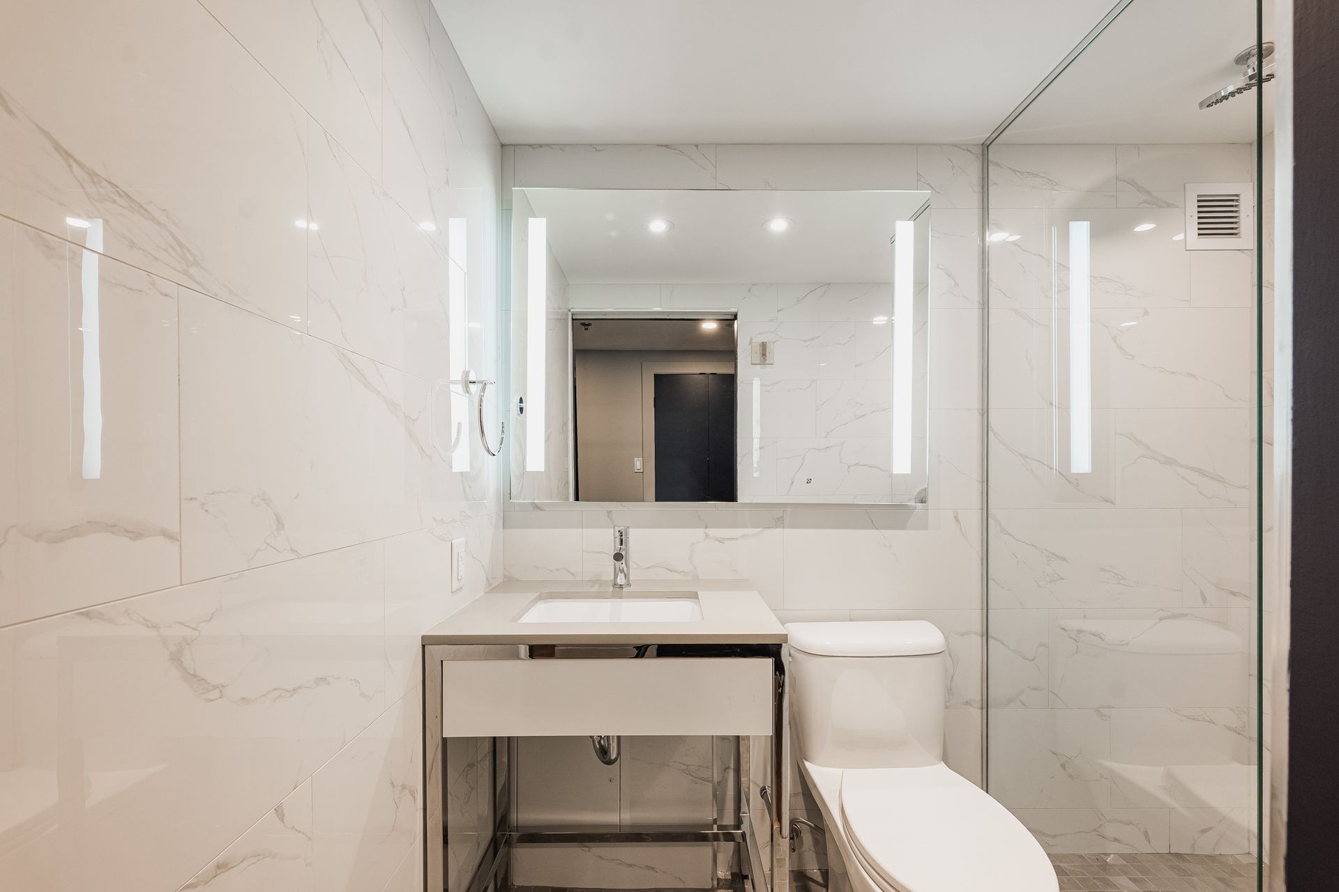Une salle de bain avec WC, lavabo, miroir et douche à l'italienne.