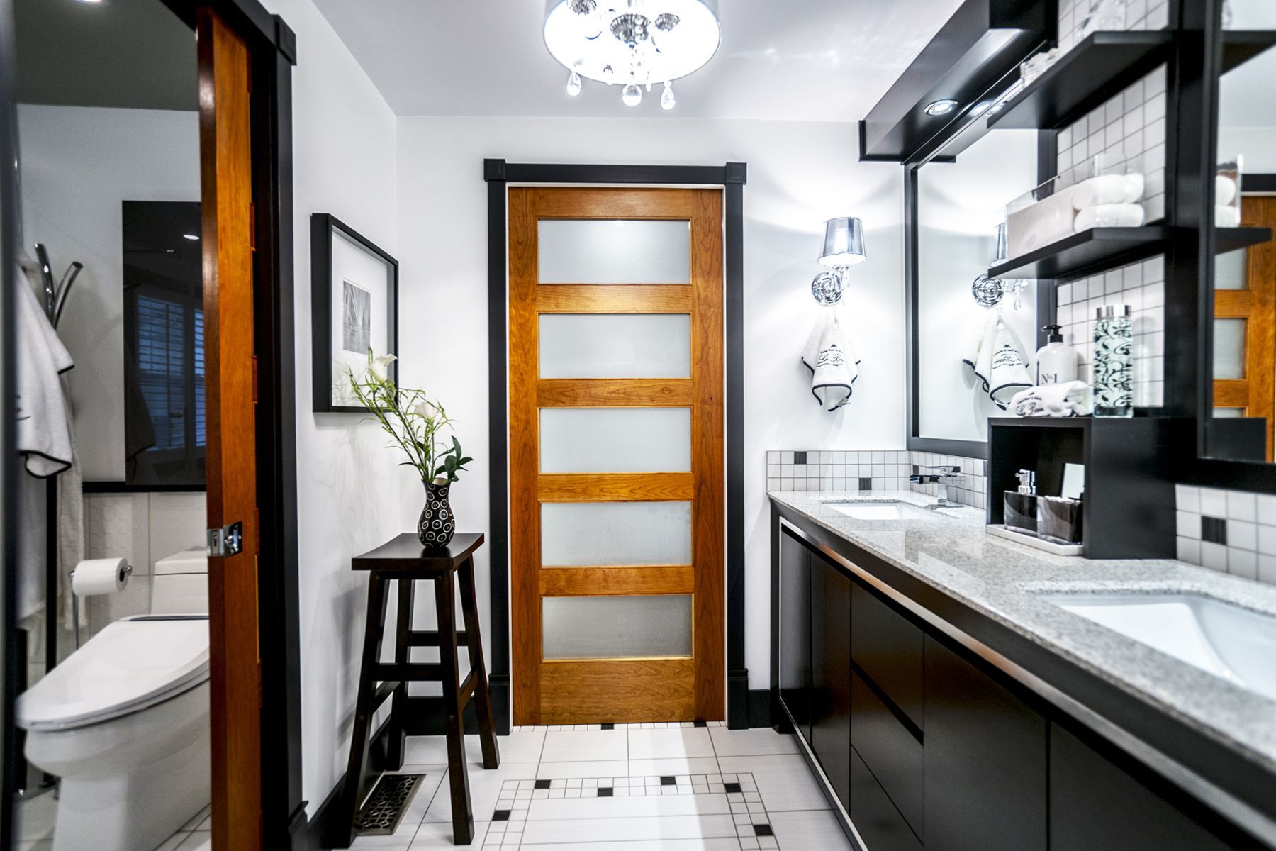 Une salle de bain avec deux lavabos , un WC et une porte en bois.