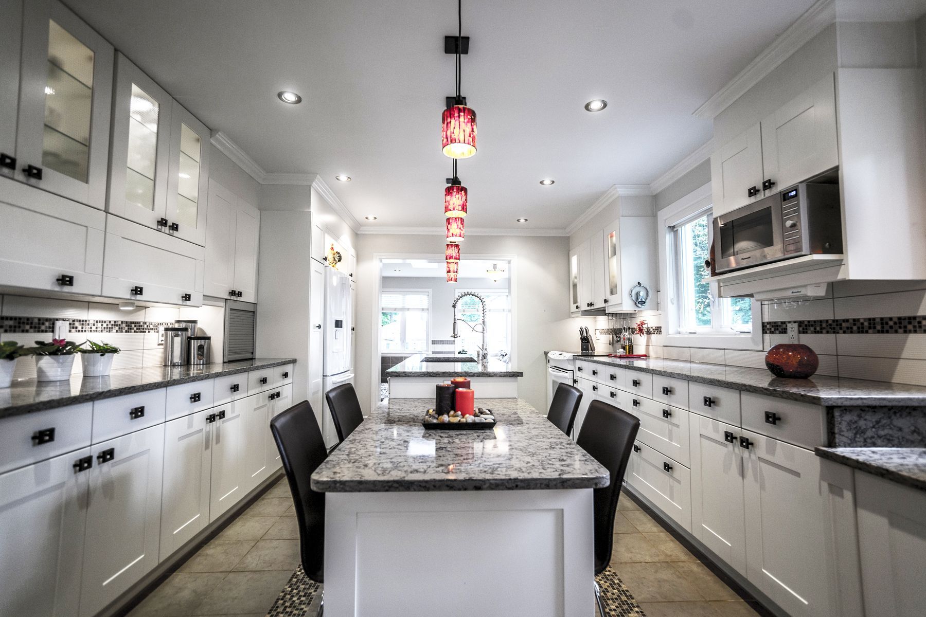 Une cuisine avec armoires blanches et comptoirs en granit