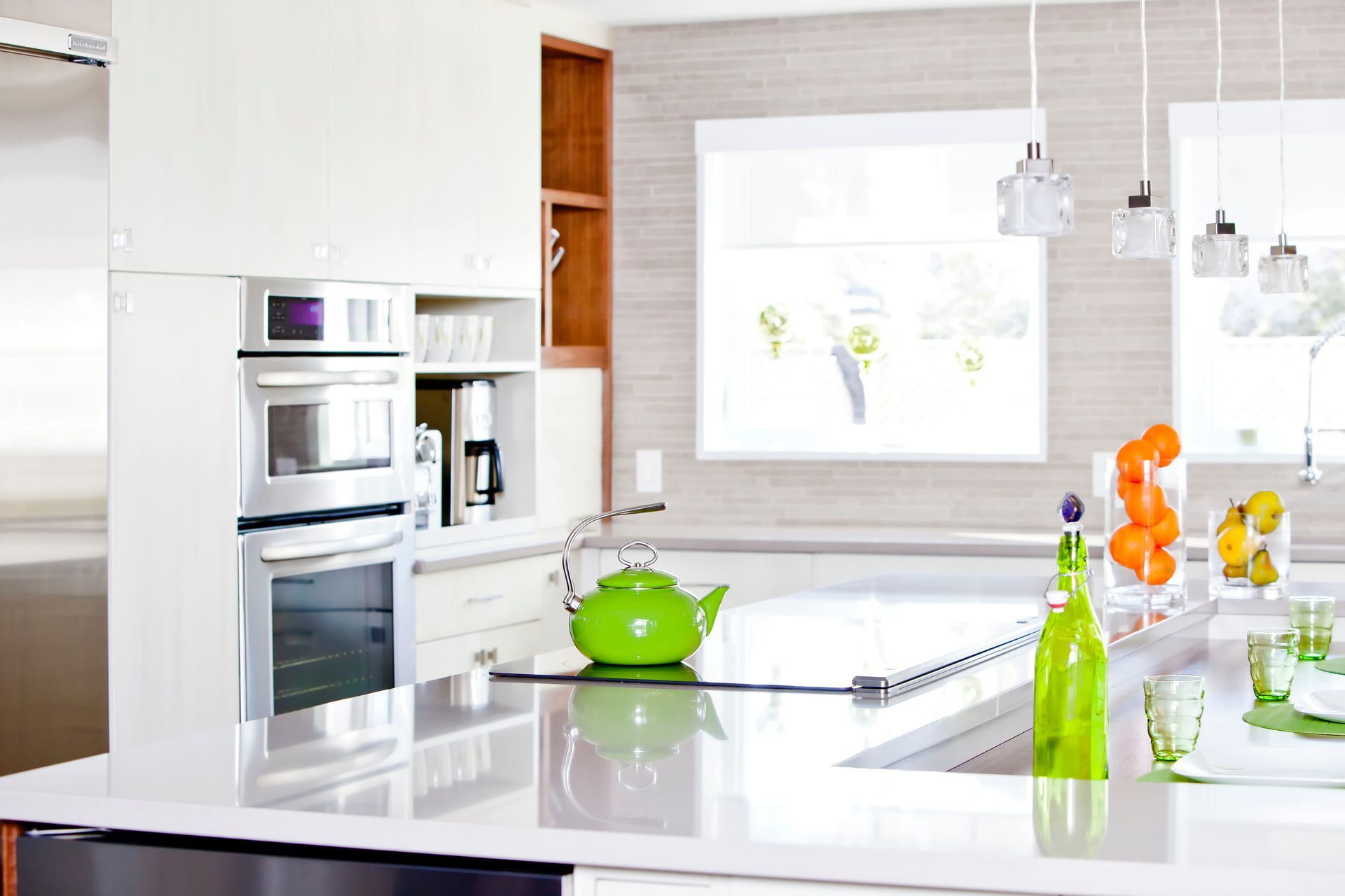 A kitchen with a green teapot on the counter