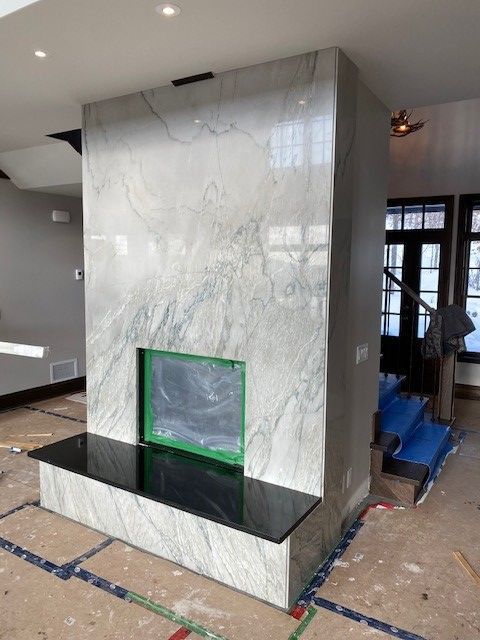 A marble fireplace with a black bench in a living room
