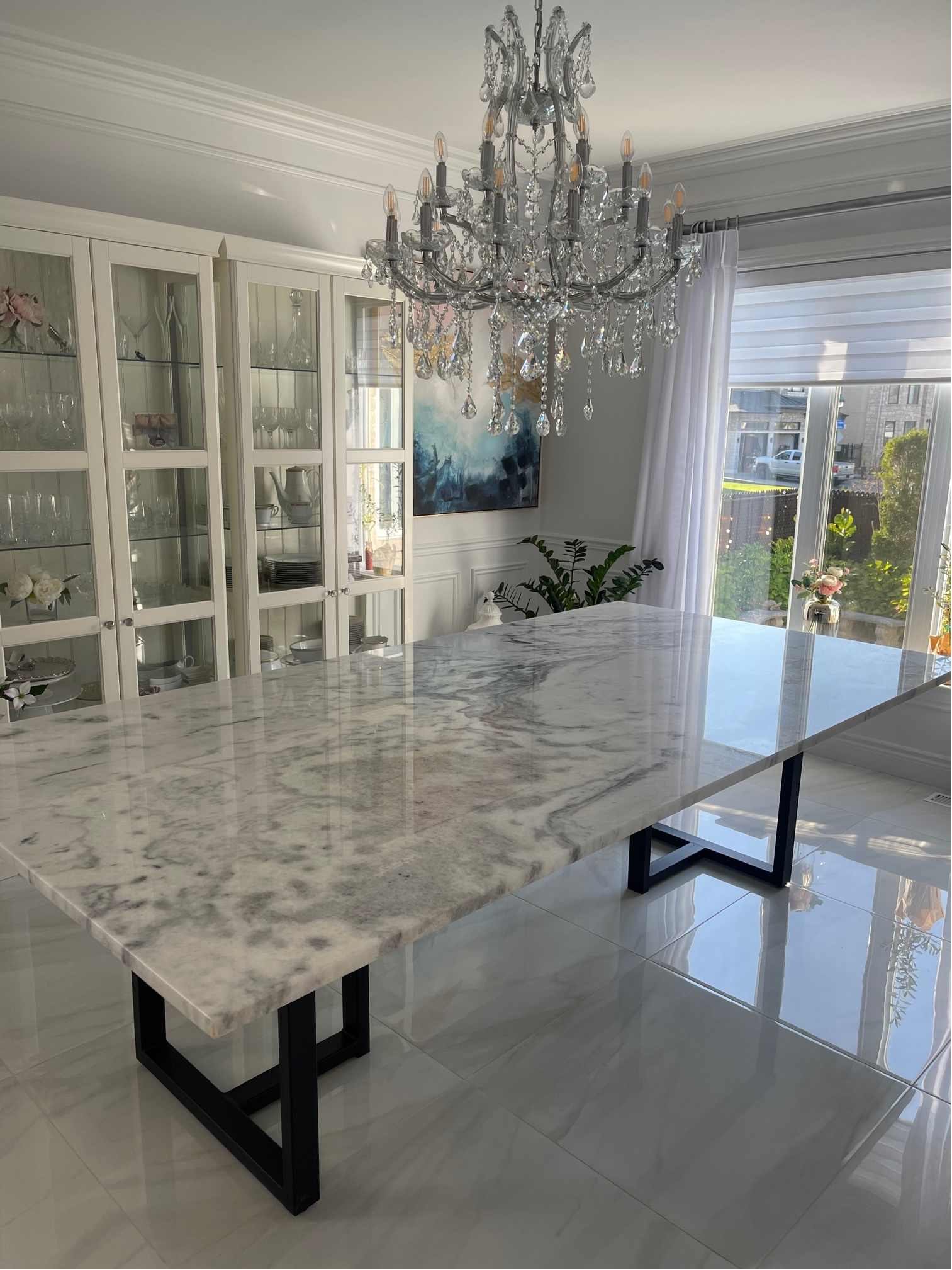A marble dining table in a dining room with a chandelier hanging from the ceiling.