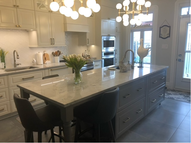 Une cuisine avec armoires blanches et un grand îlot