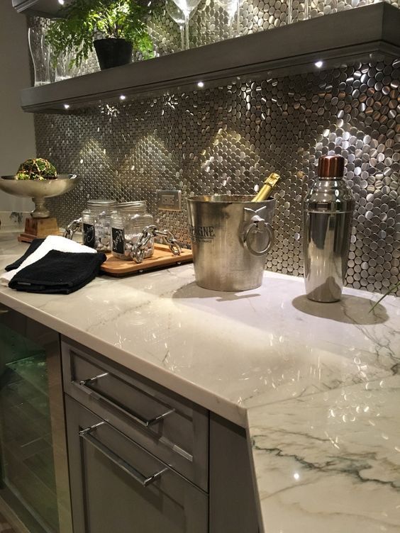 A kitchen counter with a bucket of champagne and a shaker on it.