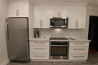 Une cuisine avec des armoires blanches, des appareils électroménagers en acier inoxydable et un réfrigérateur.