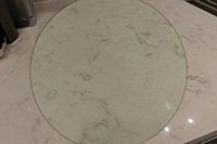 Un plateau de table rond en verre repose sur un sol en marbre.