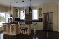 Une cuisine avec armoires blanches, appareils électroménagers en acier inoxydable et un grand îlot.