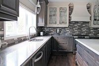 Une cuisine avec armoires grises et comptoirs blancs.