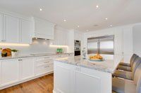 Une cuisine avec des armoires blanches, des comptoirs en marbre et des appareils électroménagers en acier inoxydable.