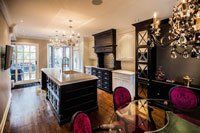 Une cuisine avec un grand îlot, une table à manger, des chaises et un lustre.