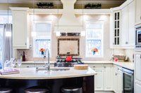 Une cuisine avec armoires blanches, comptoirs en granit, électroménagers en acier inoxydable et un grand îlot.