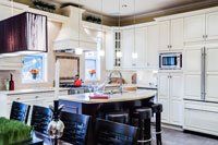 Une cuisine avec armoires blanches et un grand îlot au milieu.