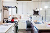 Une cuisine avec armoires blanches, appareils électroménagers en acier inoxydable et un grand îlot.