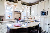 Une cuisine avec armoires blanches et un grand îlot au milieu.