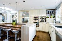 Une cuisine avec armoires blanches, appareils électroménagers en acier inoxydable et un grand îlot.