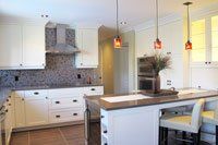 Une cuisine avec armoires blanches, comptoirs en granit et un grand îlot.