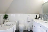 Une salle de bain avec baignoire , WC , lavabo et miroir.