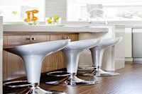 Une rangée de tabourets de bar blancs sont assis les uns à côté des autres dans une cuisine.