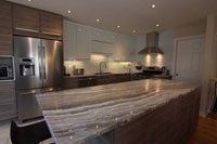 Une cuisine avec appareils électroménagers en acier inoxydable, comptoirs en granit et un grand îlot.