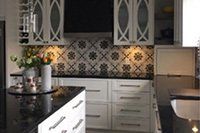 Une cuisine avec armoires blanches et comptoirs noirs.