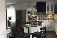 Une cuisine avec des armoires blanches, des comptoirs noirs, un réfrigérateur, une cuisinière, une table et des chaises.