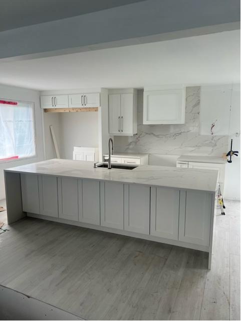 Une cuisine avec armoires blanches et un grand îlot