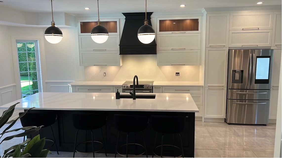 Une cuisine avec armoires blanches, appareils électroménagers en acier inoxydable et un grand îlot.