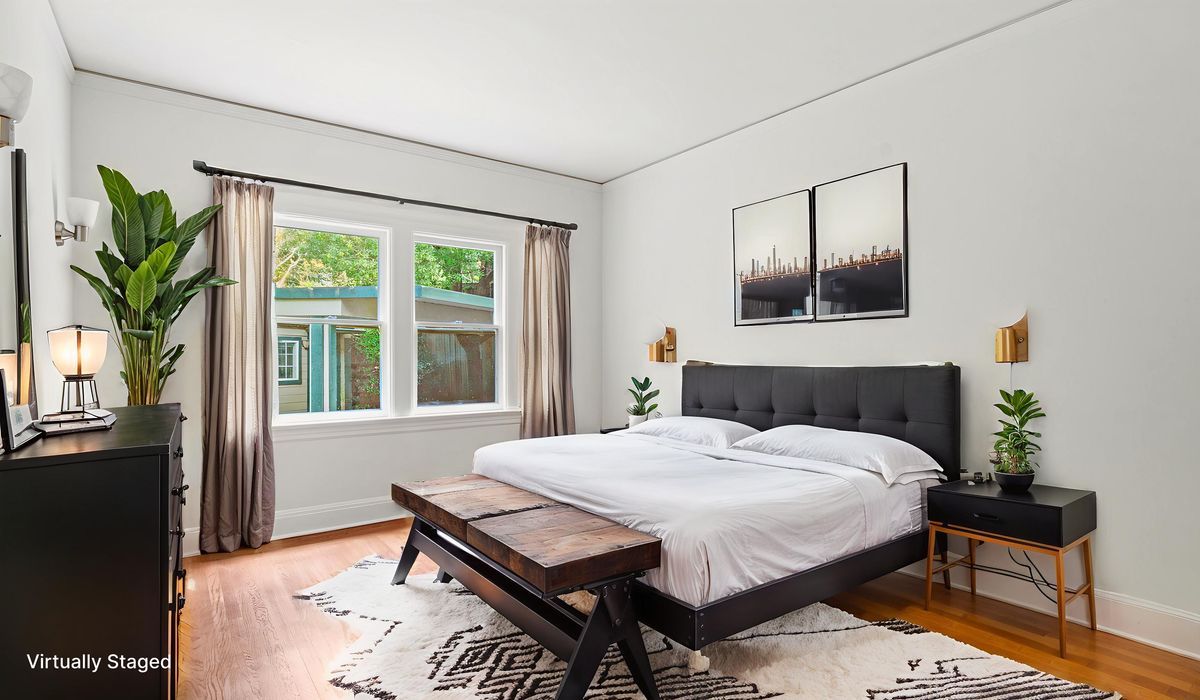 Living room with neutral tones, beige sofa, wooden chair, abstract art, and pendant lights.