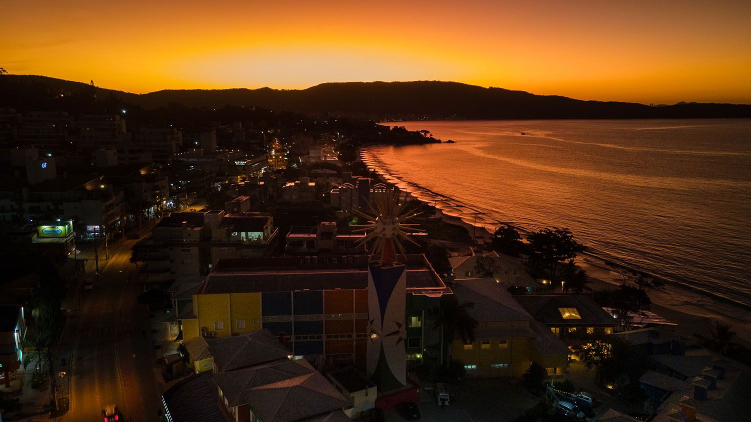 Uma vista aérea de uma cidade perto do oceano ao pôr do sol.