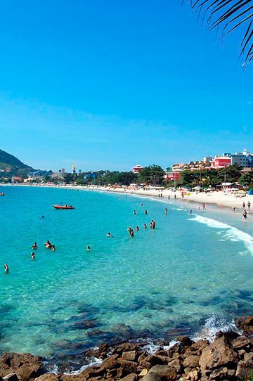 Um barco azul está parado na praia ao lado de uma árvore.