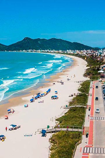 Uma vista aérea de uma praia com montanhas ao fundo.