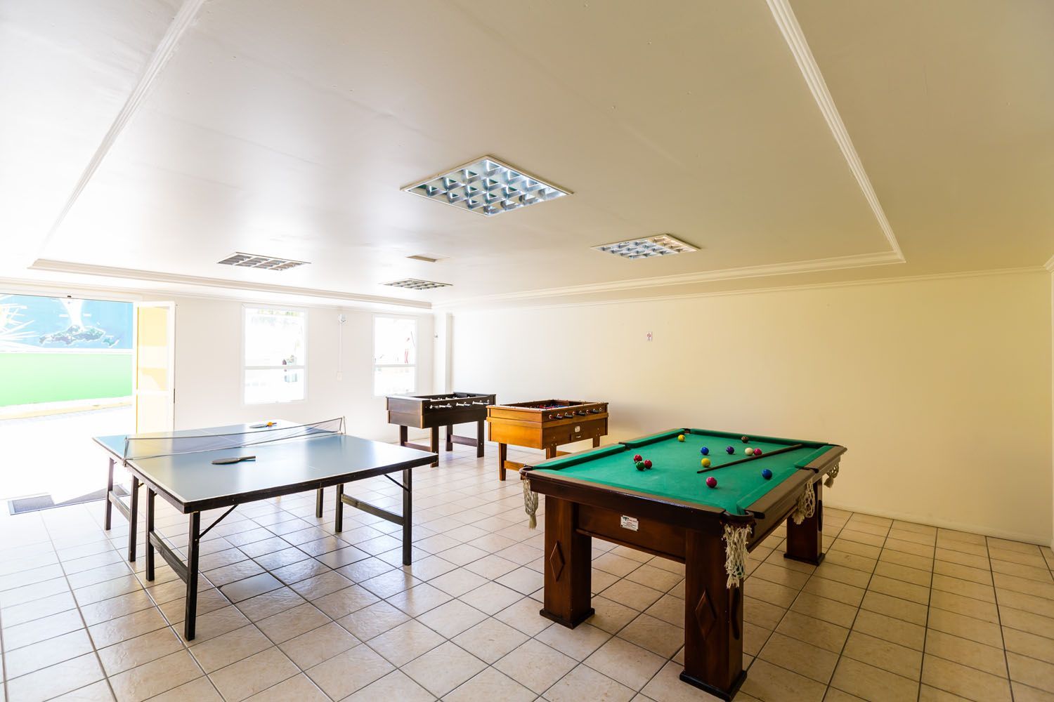 Uma sala de jogos com mesas de sinuca e mesas de pingue-pongue.