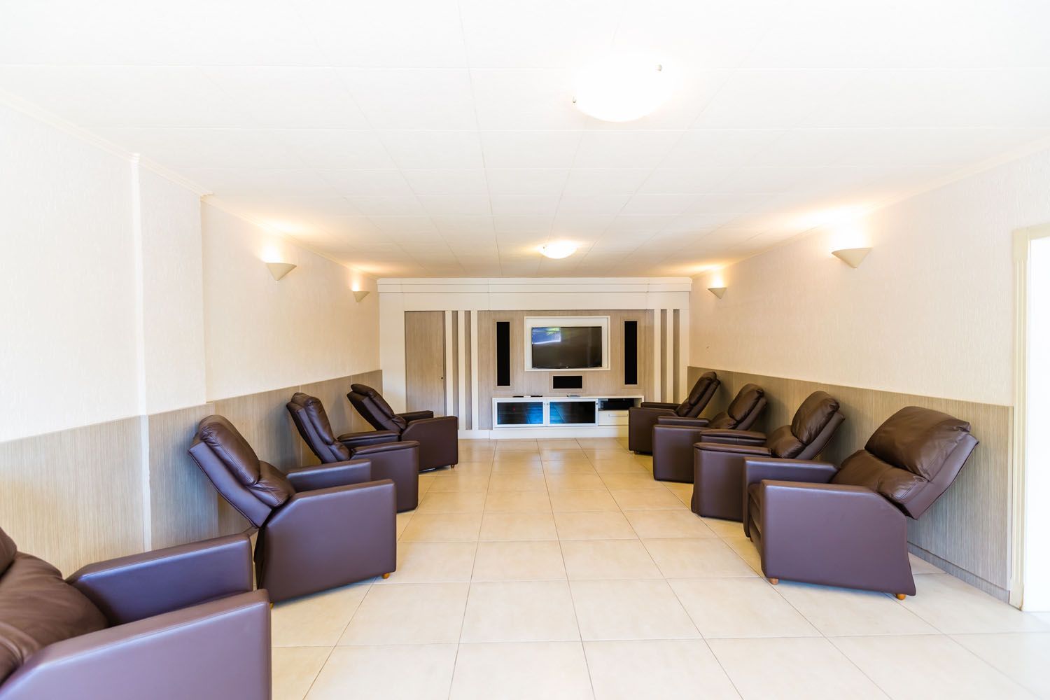 Uma sala comprida com muitas cadeiras e uma televisão.