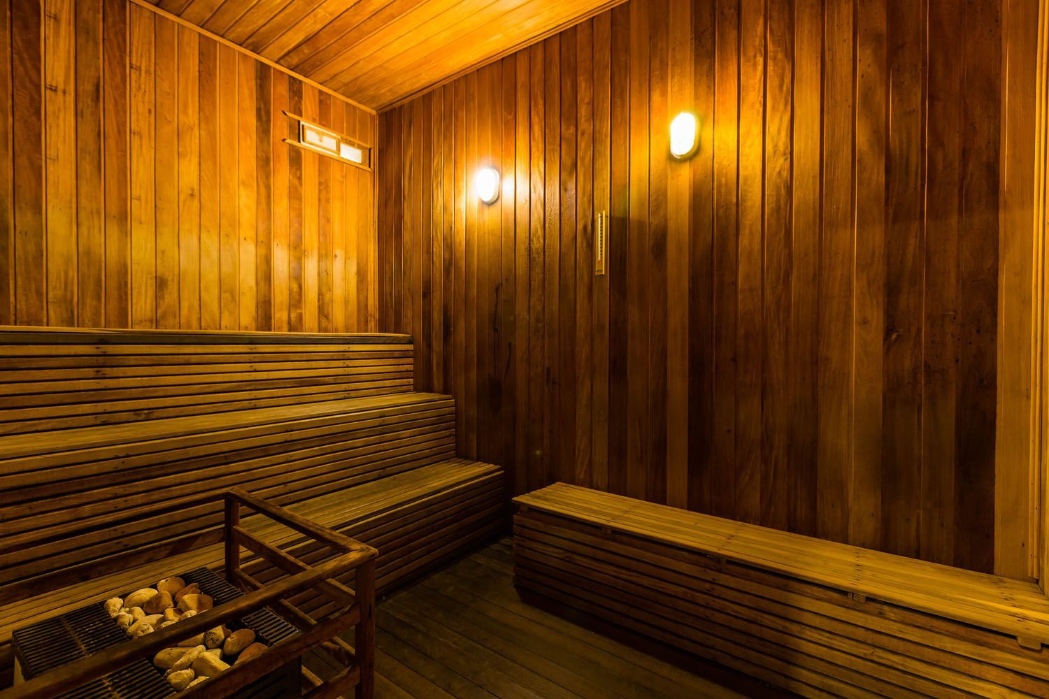 Uma sauna de madeira com muitos bancos e uma mesa.