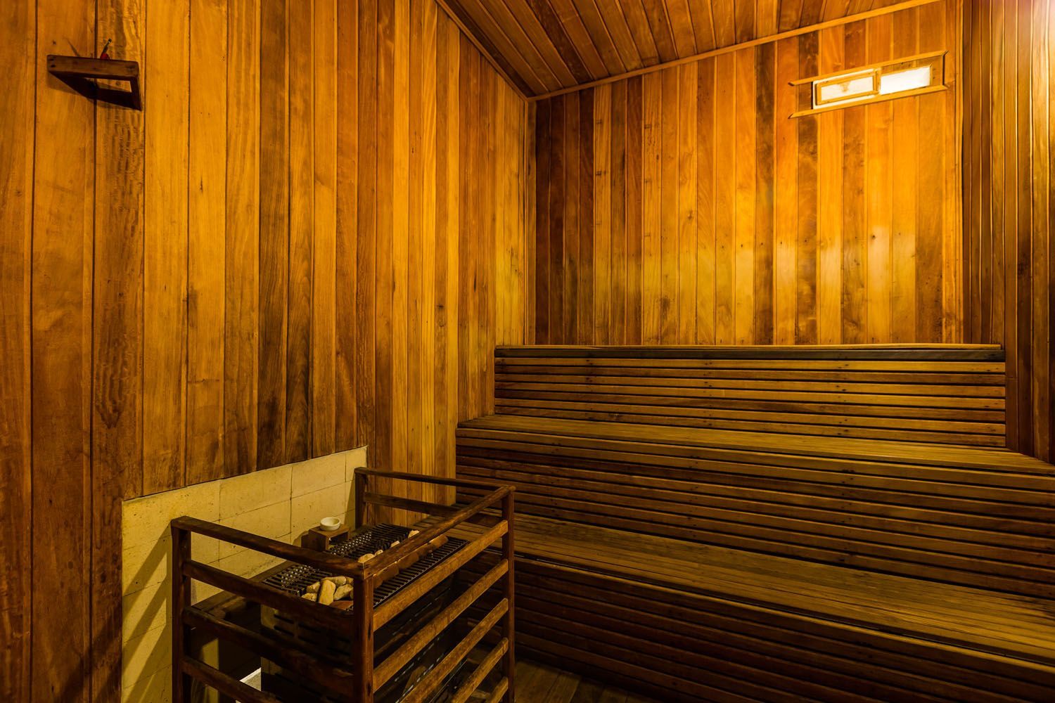Uma sauna de madeira com banco e aquecedor.