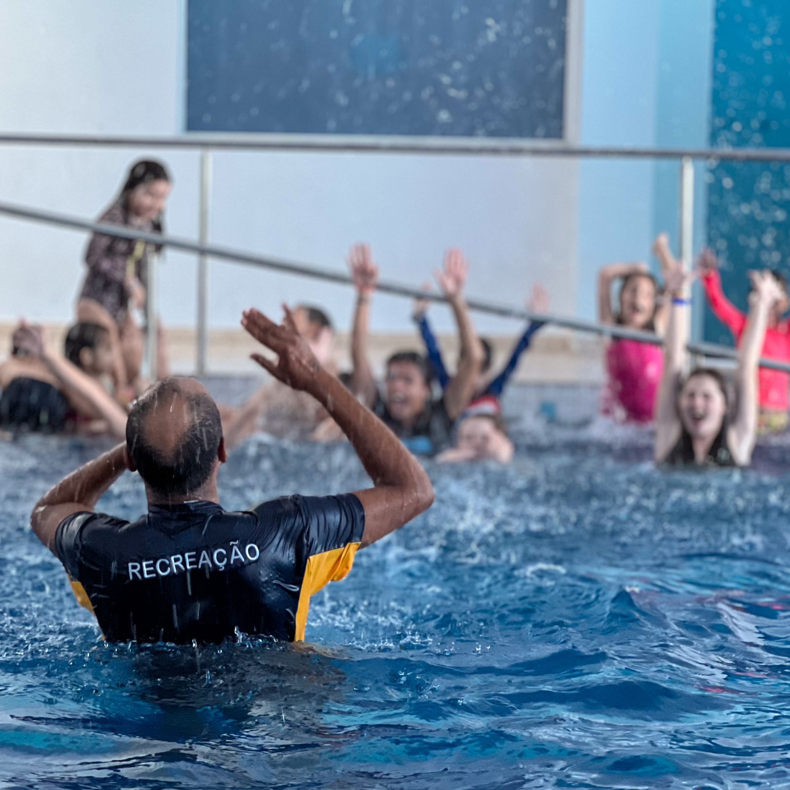 Um homem está ensinando um grupo de crianças a nadar em uma piscina.