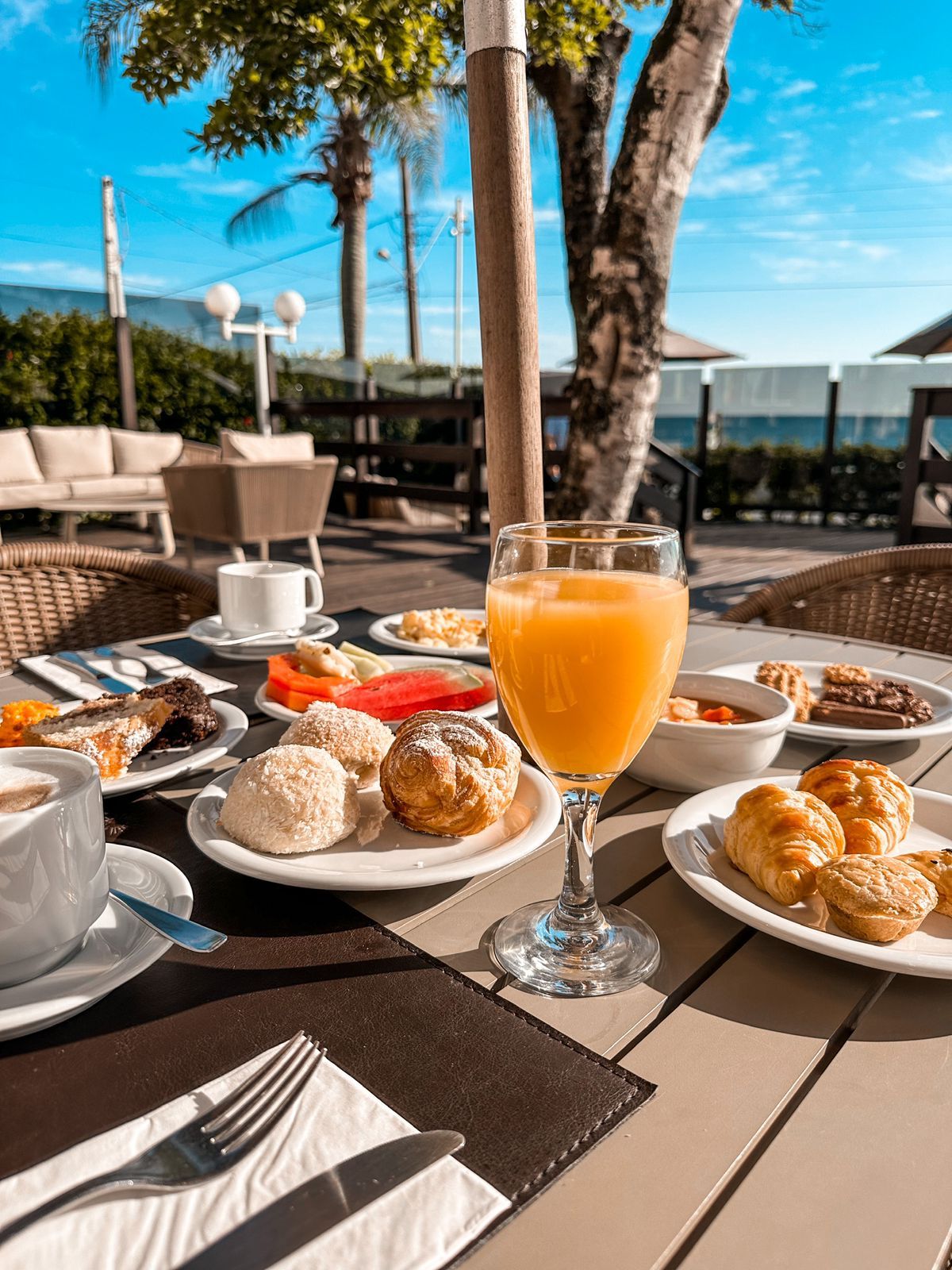 Uma mesa com pratos de comida e um copo de suco de laranja.