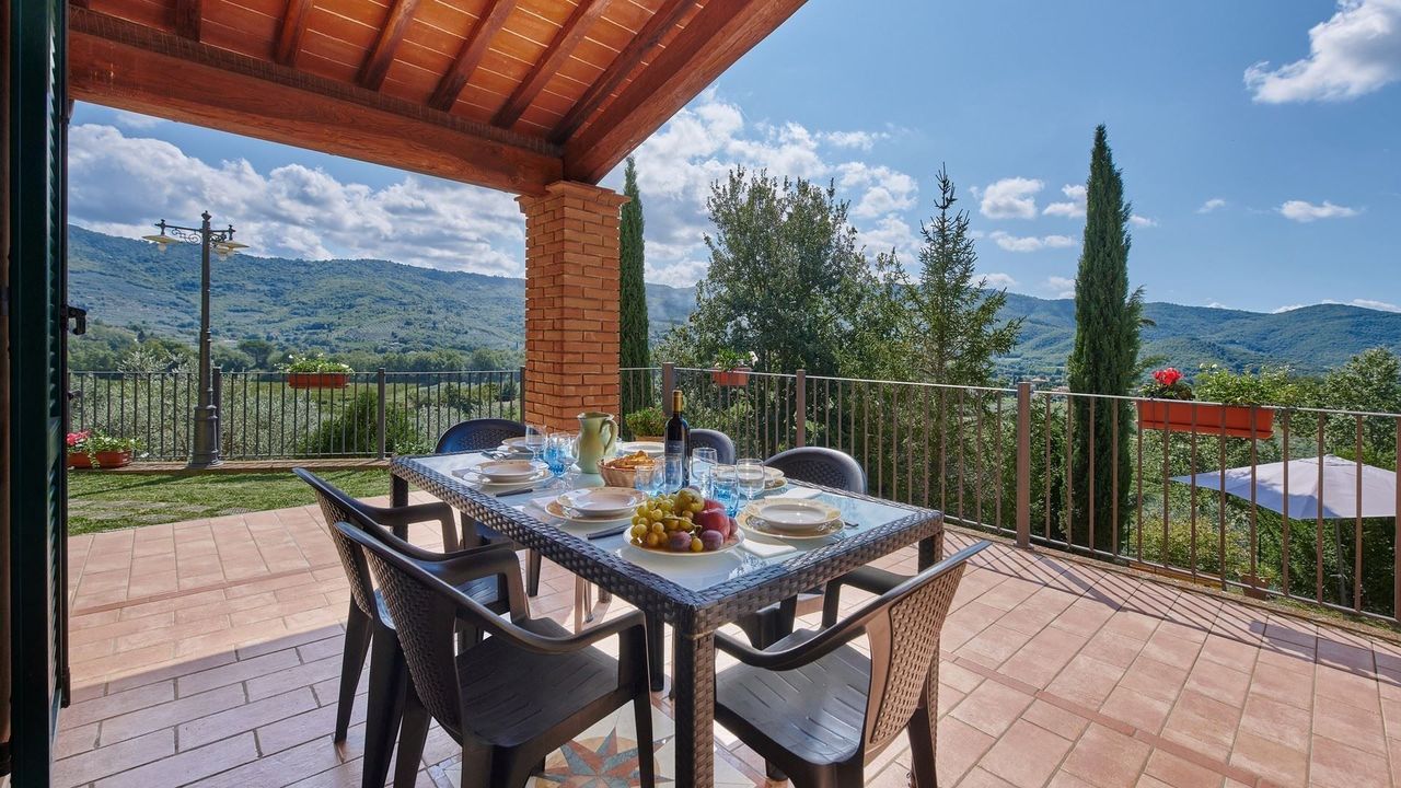 Patio dining set overlooking Tuscan hills on a sunny day.