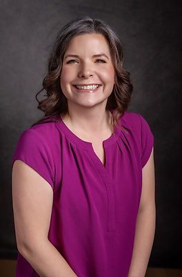 A woman in a purple shirt is smiling for the camera.